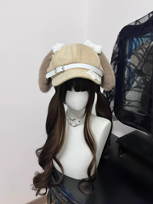 Light khaki suede newsboy cap with extra-long floppy puppy ears, white contrast stitching, and multiple silver safety pins, Grunge Harajuku style.