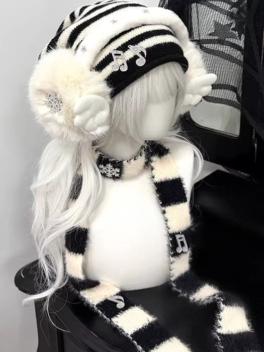 Complete 3-piece winter set featuring a black and white striped beanie, plush snowflake earmuffs, and matching long scarf with musical note charms.