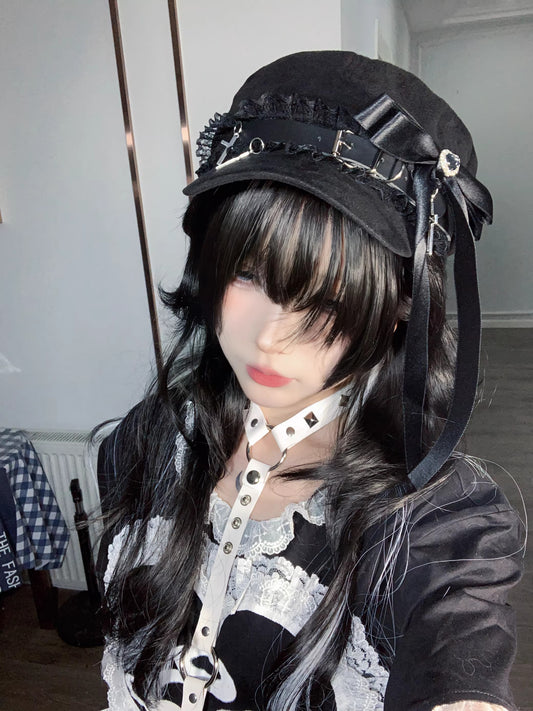Black Jirai Kei newsboy cap on a white-haired mannequin, featuring a large black satin ribbon, lace trim, and silver cross charms.