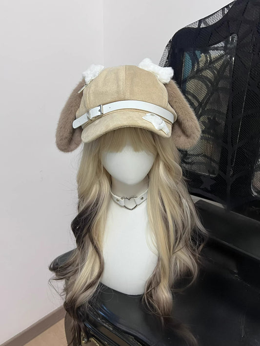 Light khaki suede newsboy cap with long floppy puppy ears, black leather strap accents with metal buckles, and white contrast stitching.