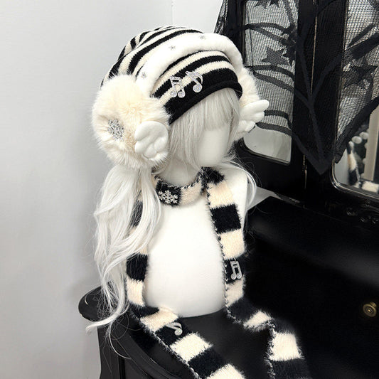 Complete 3-piece winter set featuring a black and white striped beanie, plush snowflake earmuffs, and matching long scarf with musical note charms.