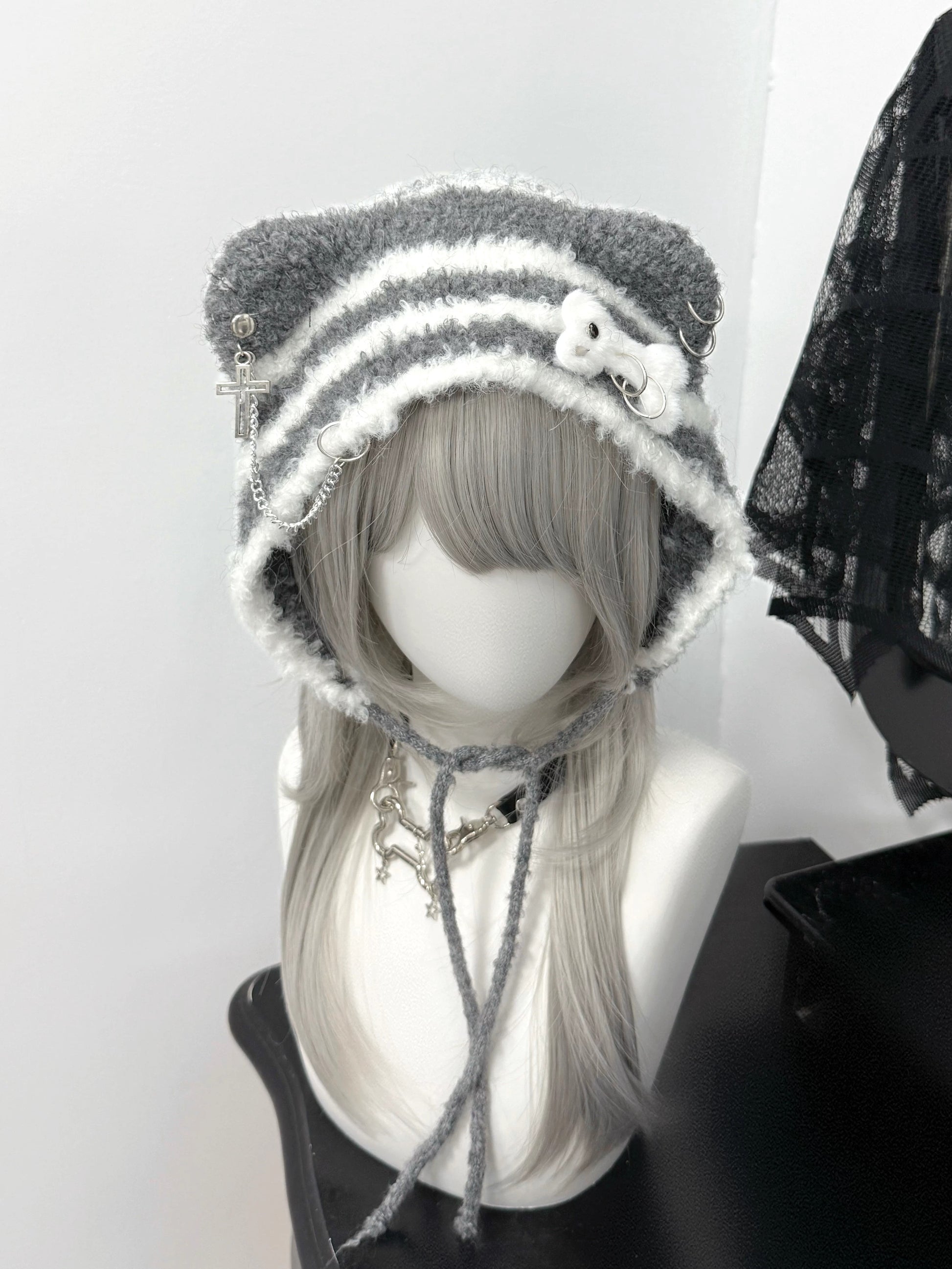 Distressed grey cat ear knit beanie with long buckle earflaps and contrast stitching.