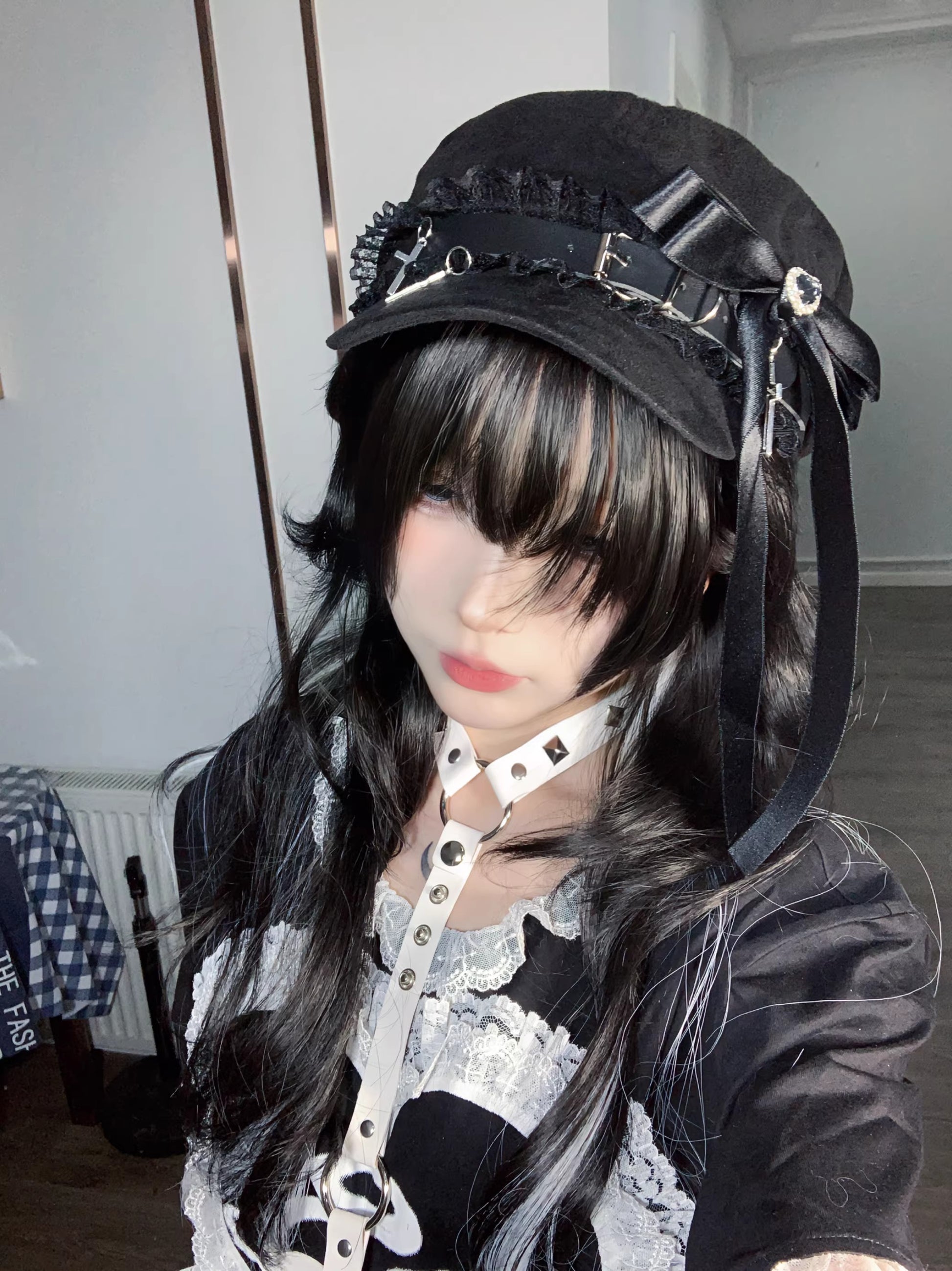 Black Jirai Kei newsboy cap on a white-haired mannequin, featuring a large black satin ribbon, lace trim, and silver cross charms.