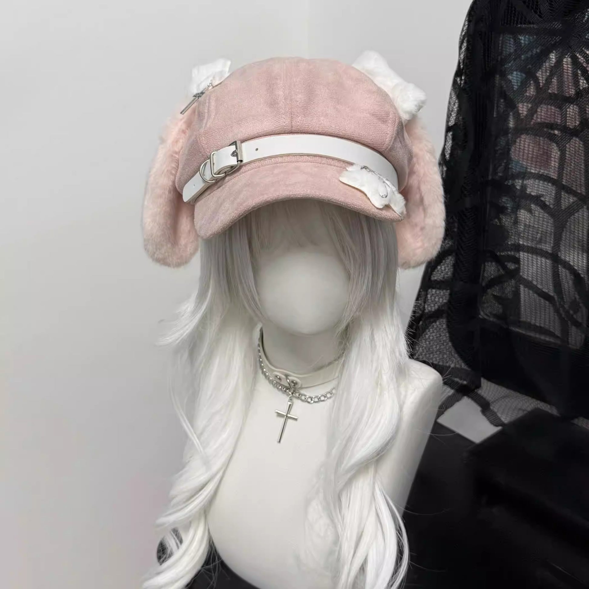 Pink newsboy cap with long white plush dog ears and a white leather belt buckle strap on a mannequin with grey hair.