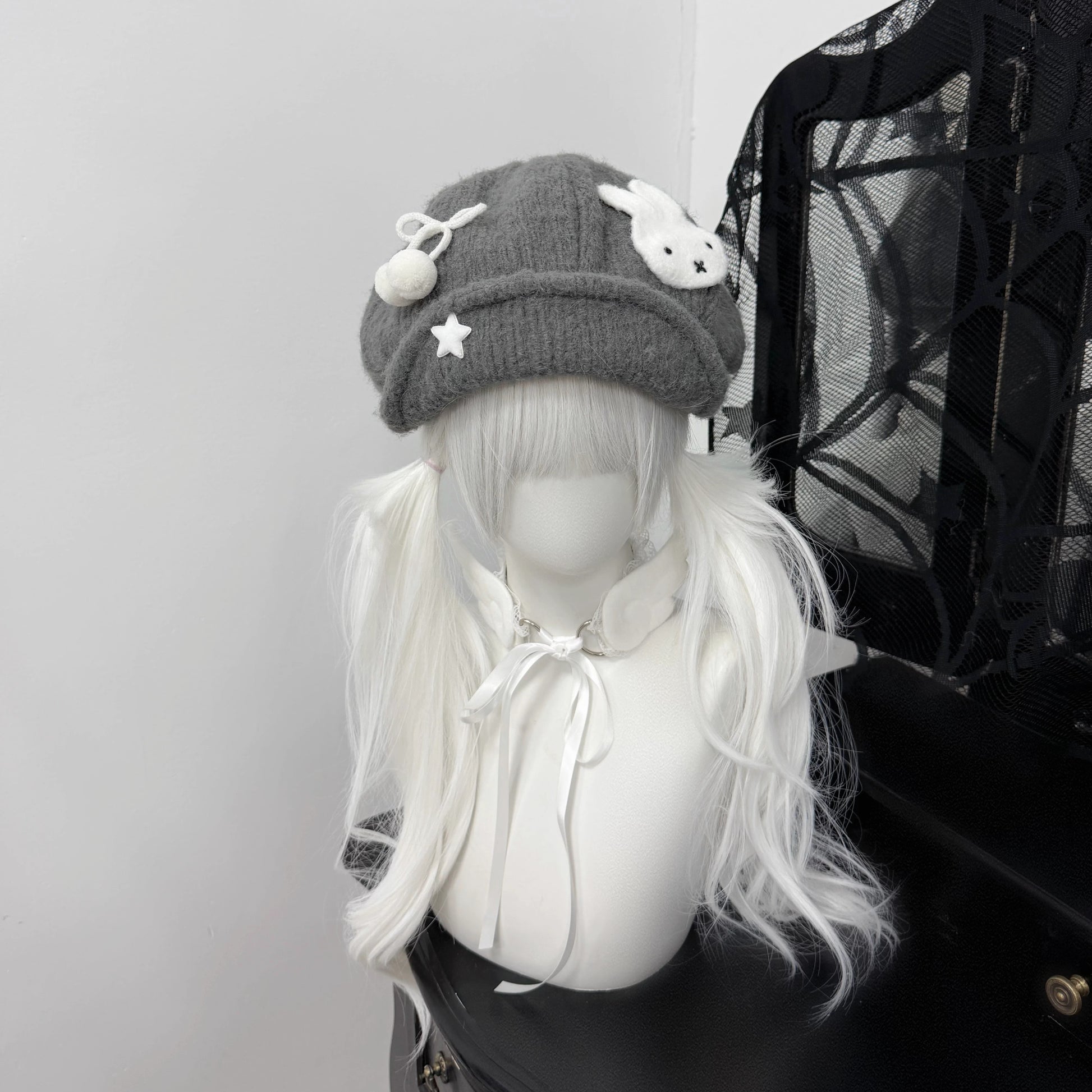 Close-up of a grey knit beret hat featuring a white Miffy bunny patch and star charms on a mannequin with white pigtails, Y2K Harajuku style fashion accessory.