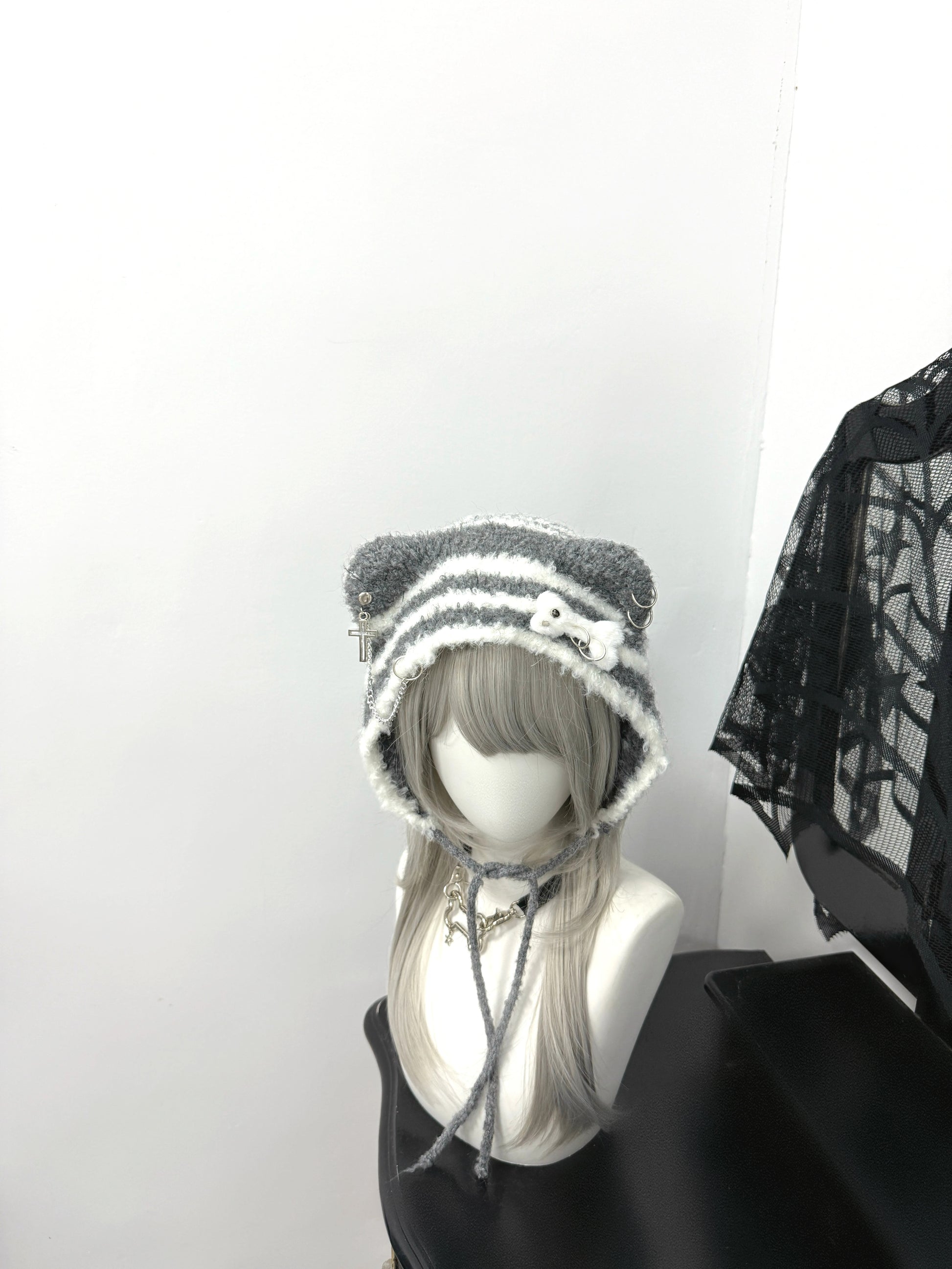 Distressed grey cat ear knit beanie with long buckle earflaps and contrast stitching.