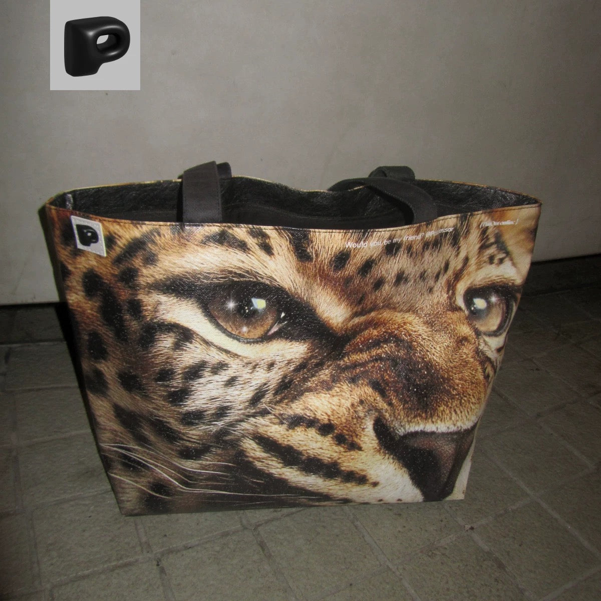 Tote bag with a leopard face design on a tiled floor.