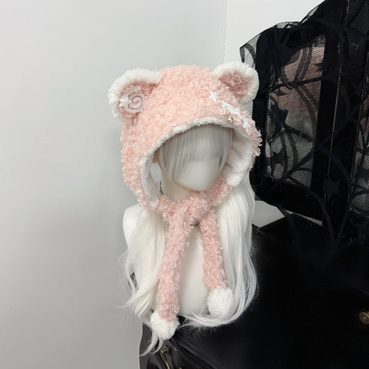 PINK fuzzy bear ear balaclava hat on a white mannequin, featuring white pom-pom ties, a metal fishbone charm, and a spiral patch, Jirai Kei fashion style.