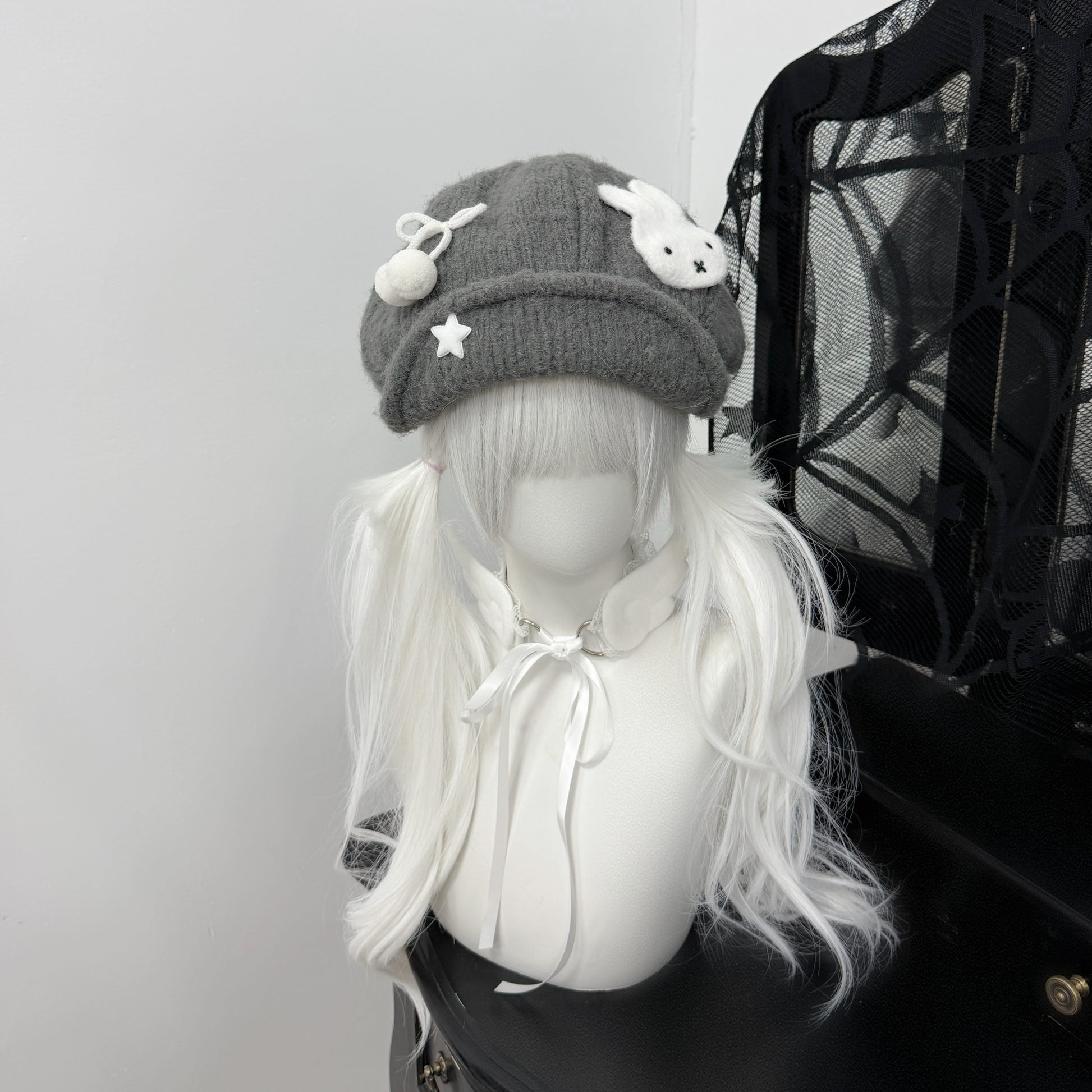 Close-up of a grey knit beret hat featuring a white Miffy bunny patch and star charms on a mannequin with white pigtails, Y2K Harajuku style fashion accessory.